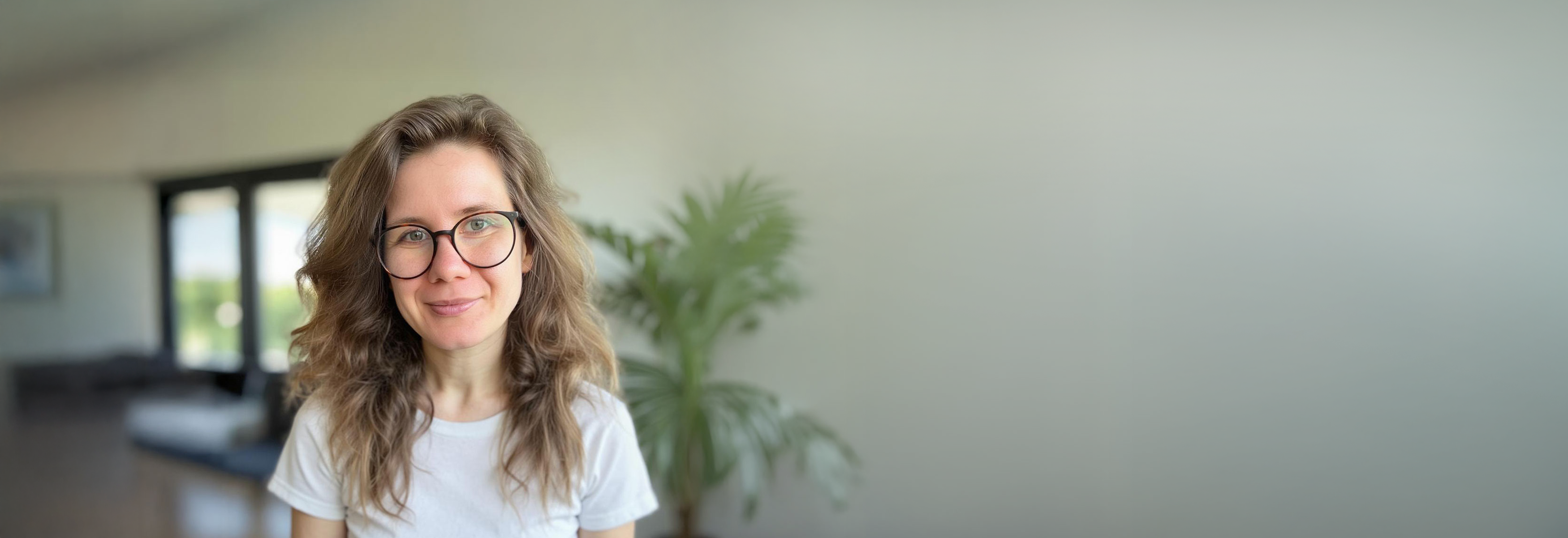 Franziska Wendling in einem hellen Raum mit Pflanze – Headerbild der Kontakt Seite
